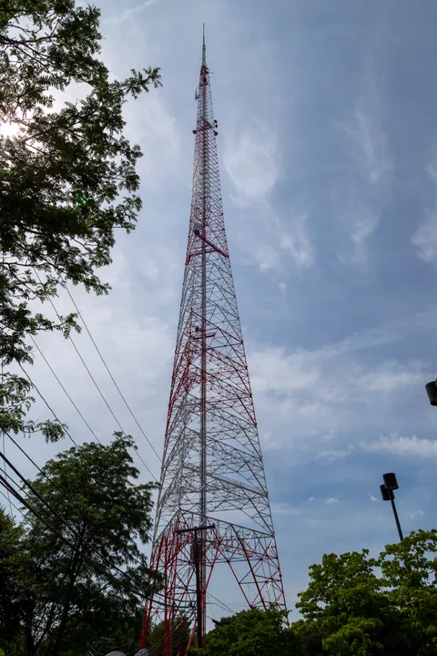 Torre de transmisión de televisión sobre una colina, rodeada de vegetación